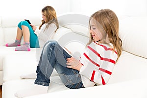 Sister friends kid girls playing with tablet pc in sofa