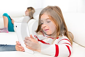 Sister friends kid girls playing with tablet pc in sofa