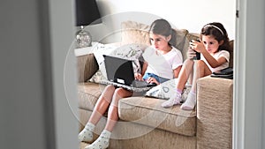 Sister girls using mobile devices during home self isolation.