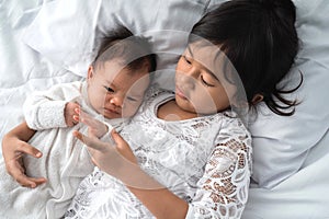 Sister with her infant newborn baby sibling play together