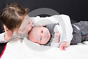 Sister kissing his little brother Child toddler girl and newborn baby boy in Concept of family life