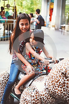 Sister`s bonding in Luna park riding a toy car