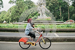 sister take her sibling riding a bike in the park