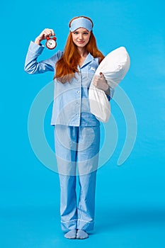 Sister telling time to bed, set alarm to wake up morning college lecture. Full-length vertical shot cute redhead