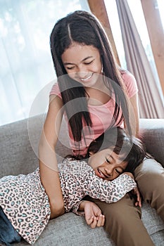 Sister tickle each other playing together