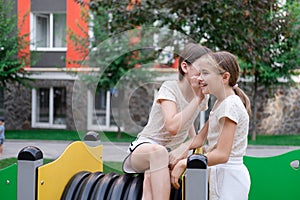 sisterhood, friendship. two charming teen girls having fun on a modern playground. sister, bffs communication photo