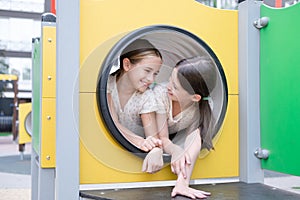 sisterhood, friendship. two charming teen girls having fun on a modern playground. sister, bffs communication photo