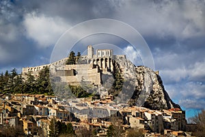 Sisteron Citadel, fortifications and rooftops with clouds. Southern Alps, Franc