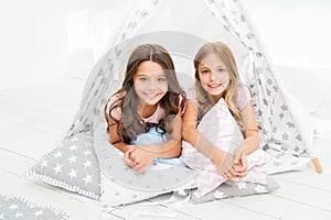 Sisters or best friends spend time together lay in tipi house. Girls having fun tipi house. Girlish leisure. Sisters photo