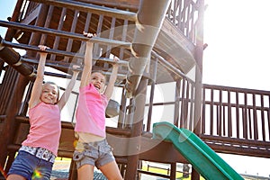 Sisters by blood, friends by choice. two little girls hanging on the monkey bars at the playground.