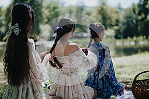 Sisters bonding in a sunny park, braiding hair by a serene pond