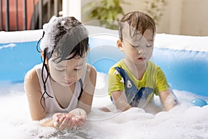 Sisters and brothers are happy to play with water bubbles in the inflatable pool.