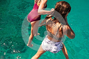 Sisters diving in the sea hand to hand enjoying summer in Zakynthos island in Greece.