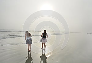 Sisters enjoying time together on beautiful foggy beach.