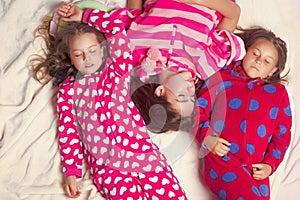 Sisters or friends in pajamas sleep in bed, top view. Good night, napping, bedtime, slumber, dream, sleepover concept.