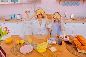 Sisters leading healthy lifestyle holding halves of oranges near faces