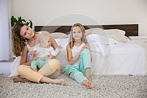 Sisters play with the baby on the bed in the bedroom