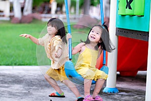 Sisters play happy swings. Older sister swing and run to the side. Brethren play together on the playground.