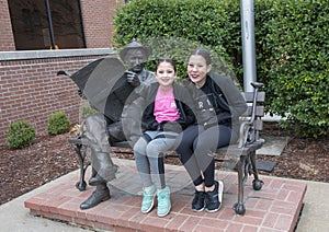 Sisters posing with bronze of Will Rogers on a bench, Claremore, Oklahoma