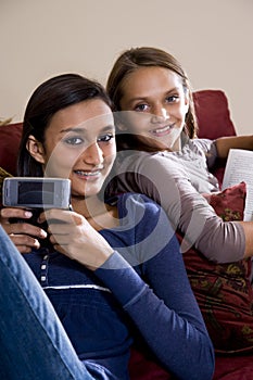 Sisters relaxing together at home on sofa