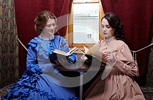 Sisters in retro dress reading books in train compartment