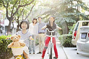 Sisters Ride Their Bicycles While Parents Watch