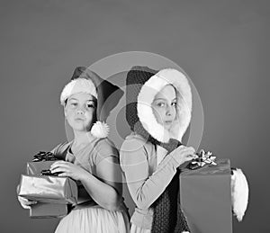 Sisters in Santa Claus hats with gift boxes receive present.