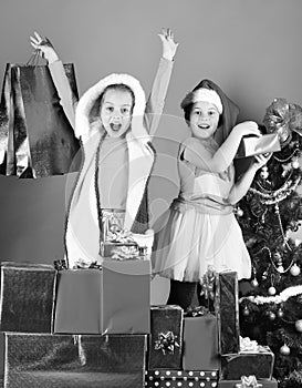 Sisters in Santa Claus hats with gift boxes receive presents.
