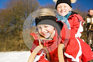 Sisters in snow on toboggan