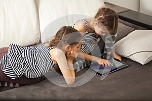 Sisters with tablet on couch at home