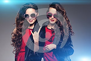 Sisters twins in hipster sun glasses laughing. Two fashion model