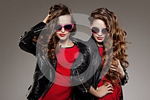 Sisters twins in hipster sun glasses laughing Two fashion models