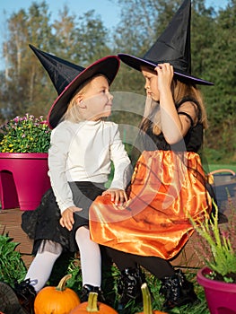 Sisters in witch costumes looking at each other outdoors