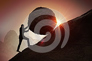 Sisyphus metaphore. Silhouette of businessman pushing heavy stone boulder up on hill