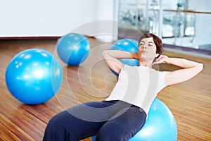 Sit up exercise. Woman doing sit ups using fitness ball in a gymnasium.