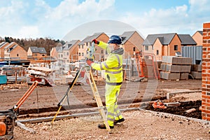 Site engineer in hi-viz installing surveying instrument on construction site