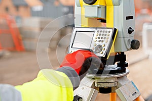 Site engineer in hi-viz working on house building construction site using modern surveying equipmen