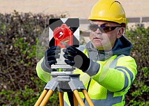 Site engineer installing back sight prism above control points on construction site