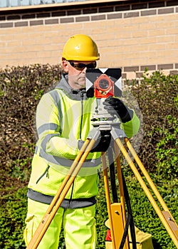 Site engineer installing back sight prism above control points on construction site