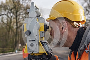 Site engineer operating his instrument during roadworks. Builder using total positioning station tachymeter on construction site