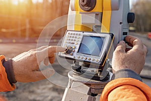 Site engineer operating instrument during roadworks. Builder using total positioning station tachymeter on construction site
