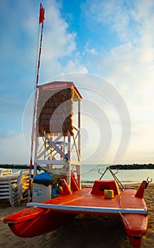 The site of the lifeguard on the beach during sunrise with his paddle boat