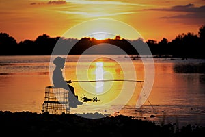 A sits on the river and catches fish. A photo of the silhouette under the sun