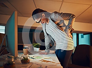 Sitting all day is giving her back problems. a young businesswoman experiencing body discomfort in the office.