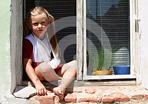 Sitting barefeet girl in a window with broken hand