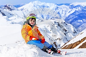 Sitting boy wearing ski mask and helmet in winter
