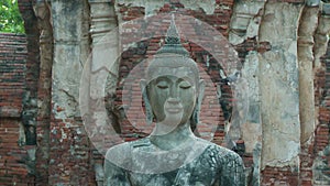 A sitting Buddha at the base of a Prang structure