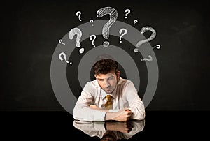 Sitting businessman under question marks