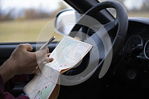 Sitting in the car driver hands holding the map and searching the way out, lost in forest f