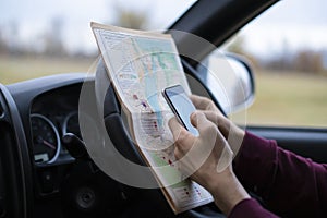 Sitting in the car driver hands holding the map and searching the way out, lost in forest f